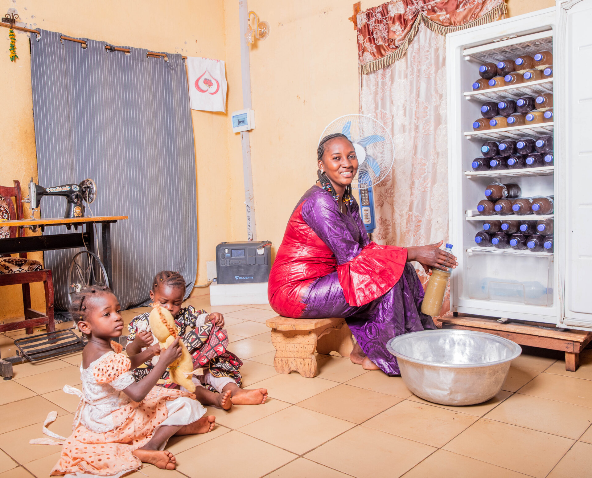 Tinta Setou placing juice jugs in a refrigerator